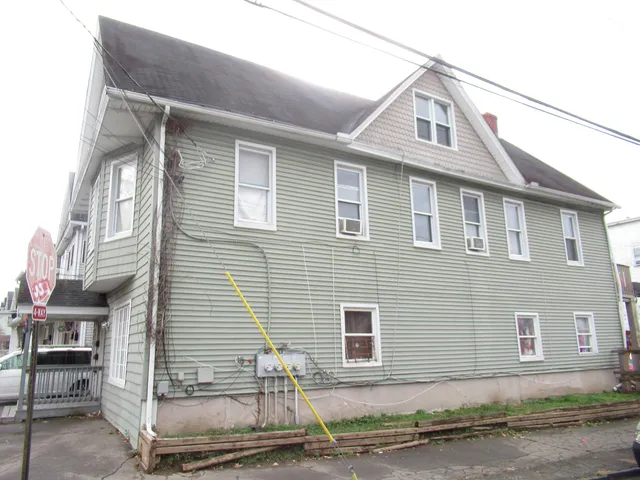 a white building with a small yard and plants