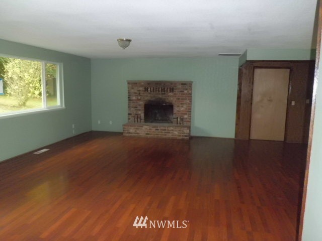 578 Brown Road East Chehalis, WA 98532 - Photo 7 of 16 an empty room with wooden floor a fireplace and windows
