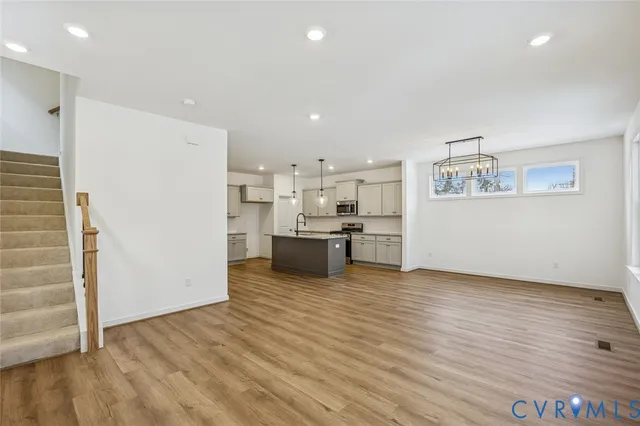 a view of a kitchen with kitchen island wooden floors stainless steel appliances and cabinets