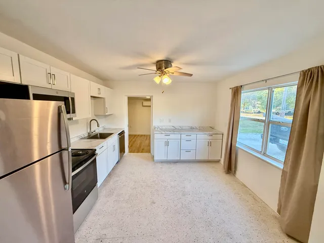 a kitchen with stainless steel appliances a refrigerator a stove a sink and a refrigerator with wooden floor