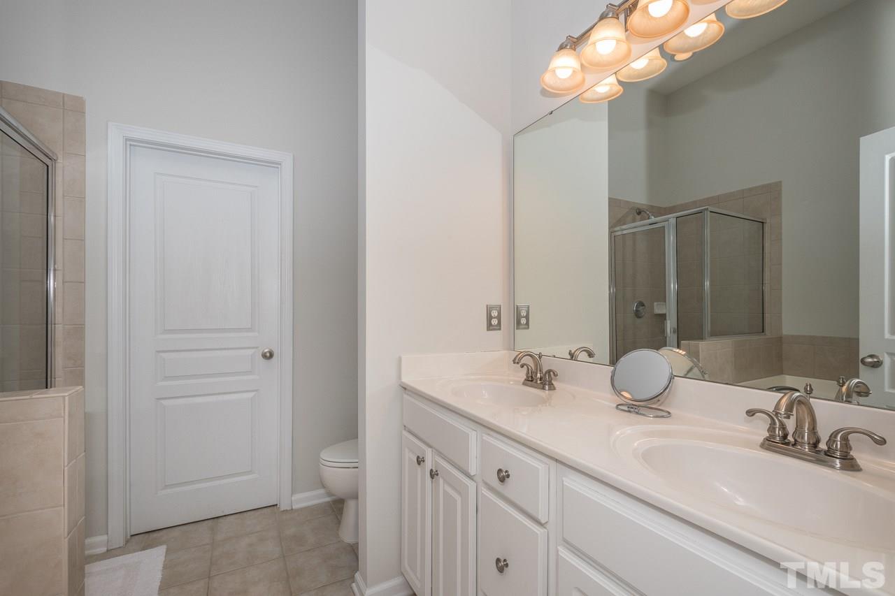 4924 Amber Clay Lane Raleigh, NC 27612 - Photo 18 of 24 a bathroom with a double vanity sink and a mirror