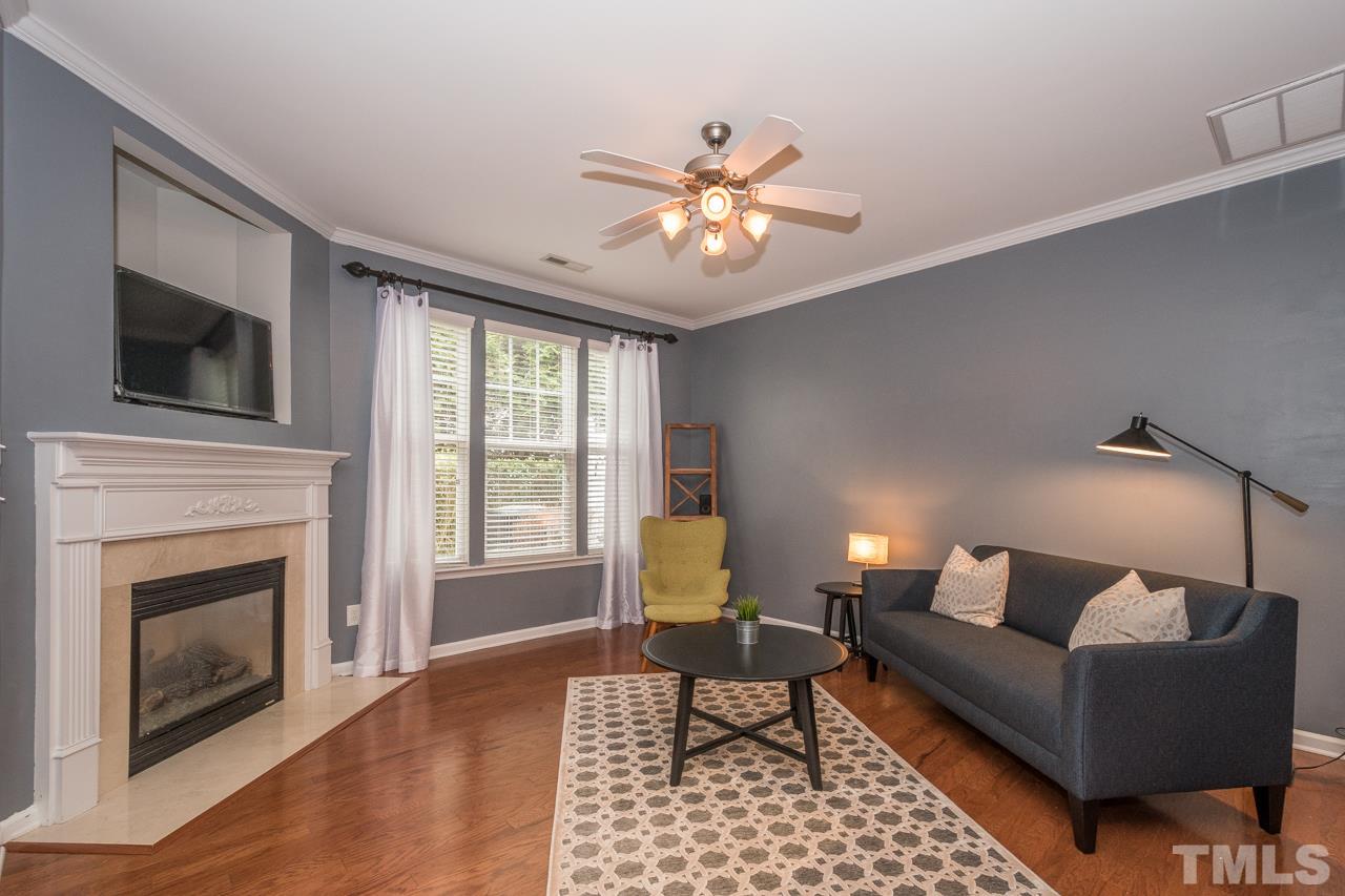 4924 Amber Clay Lane Raleigh, NC 27612 - Photo 5 of 24 a living room with furniture a fireplace and a flat screen tv