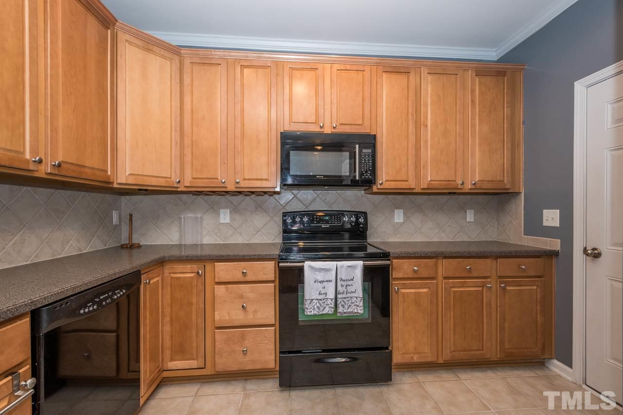 4924 Amber Clay Lane Raleigh, NC 27612 - Photo 9 of 24 a kitchen with granite countertop a stove top oven microwave and cabinets