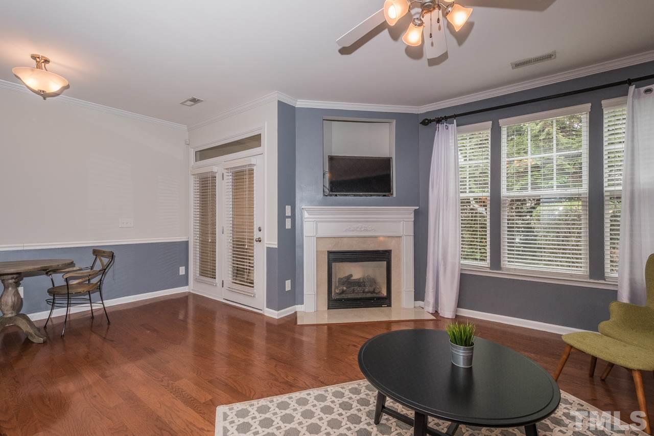 4924 Amber Clay Lane Raleigh, NC 27612 - Photo 10 of 24 a living room with furniture a fireplace and a flat screen tv