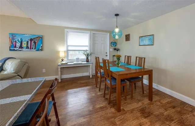 a kitchen with stainless steel appliances kitchen island granite countertop a dining table chairs and a refrigerator