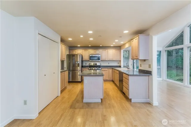 a large kitchen with stainless steel appliances granite countertop a large counter top a stove and a sink