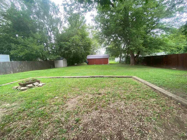 a backyard of a house with large trees and wooden fence