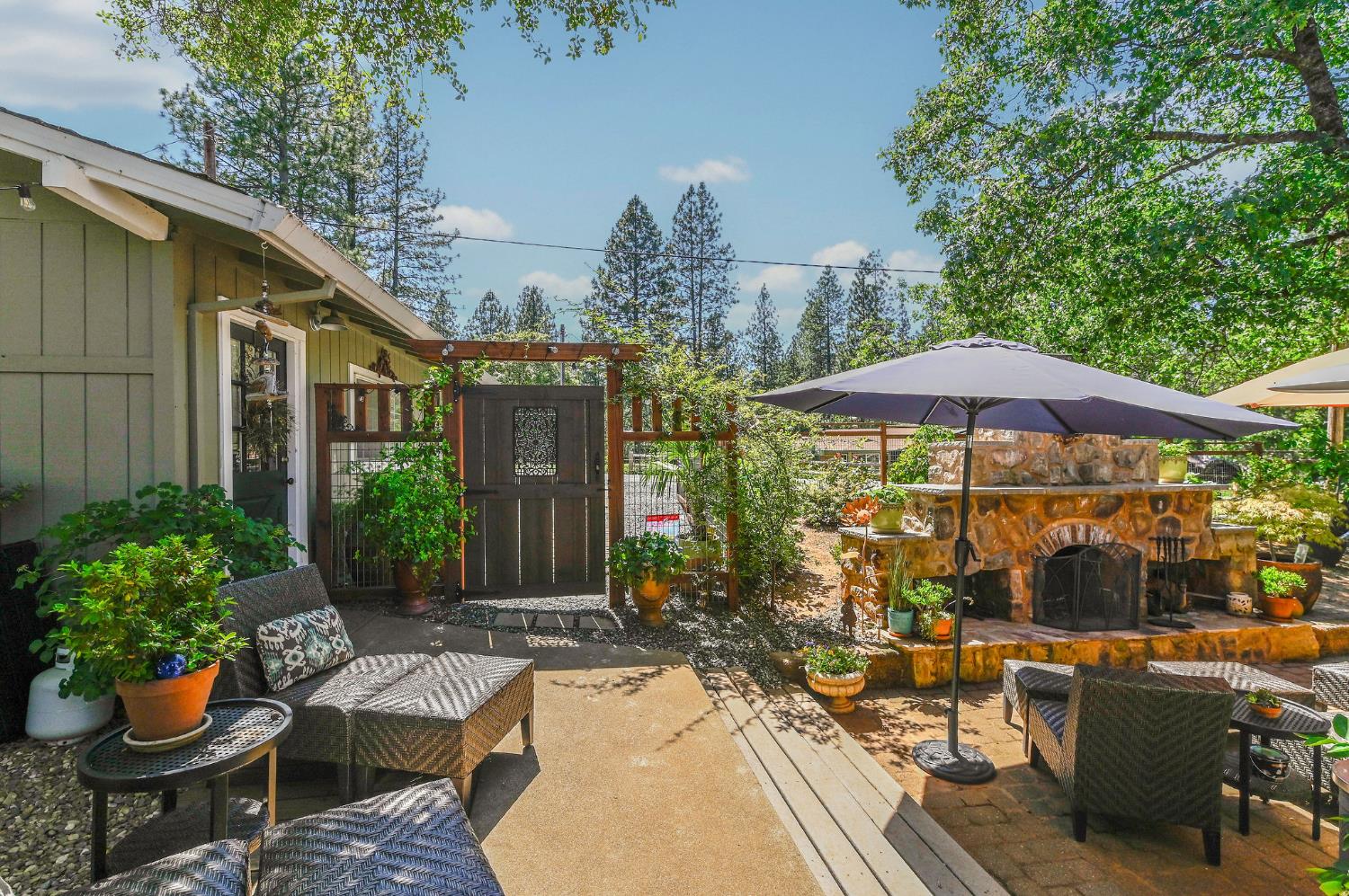 11266 Clinton Bar Road Pine Grove, CA 95665 - Photo 74 of 77 a view of a patio with couches table and chairs under an umbrella