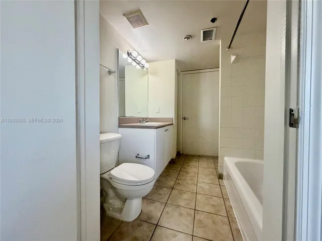 a bathroom with a granite countertop toilet a sink a mirror and shower