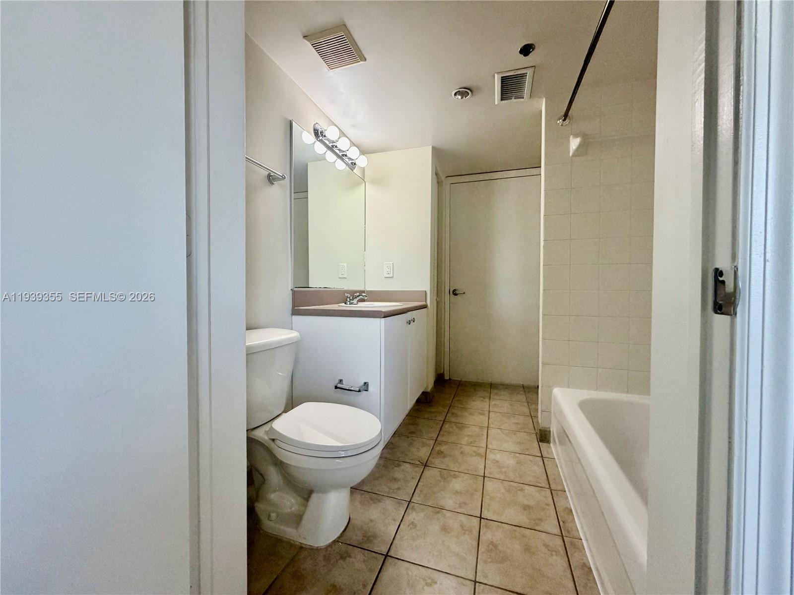 601 Southwest 37th Avenue, Unit 301 Miami, FL 33135 - Photo 7 of 22 a bathroom with a granite countertop toilet a sink a mirror and shower