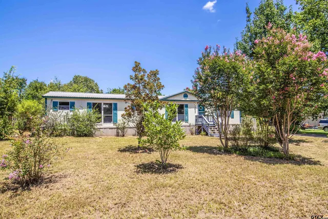 a front view of a house with a yard and potted plants