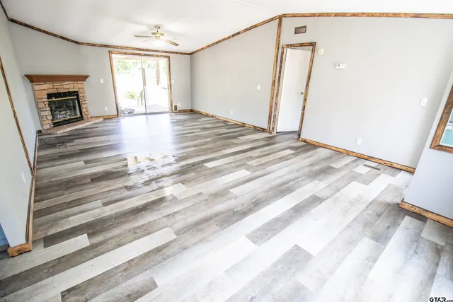 a view of an empty room with wooden floor fireplace and a window