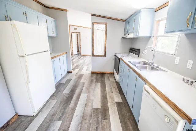 a kitchen with kitchen island wooden floor a refrigerator and a sink