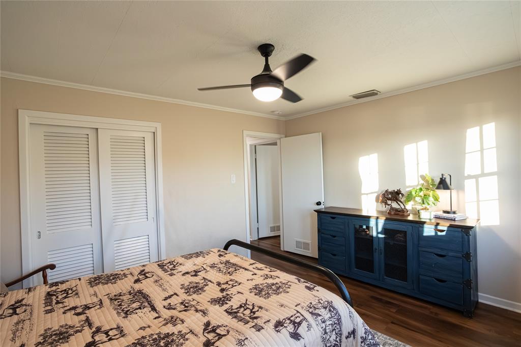 909 Cherry Street Baird, TX 79504 - Photo 19 of 32 a bedroom with a bed and wooden floor
