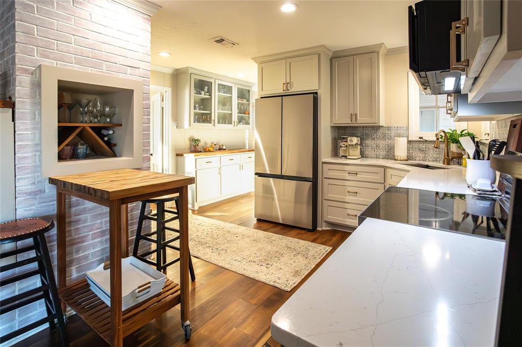909 Cherry Street Baird, TX 79504 - Photo 5 of 32 a kitchen with stainless steel appliances granite countertop a refrigerator a stove a sink dishwasher and white countertops with wooden floor