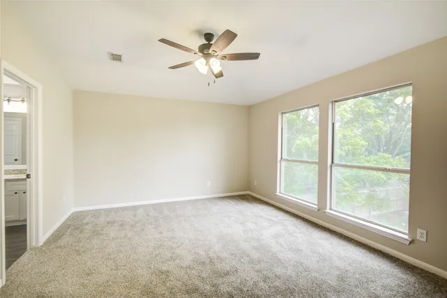 an empty room with windows and fan