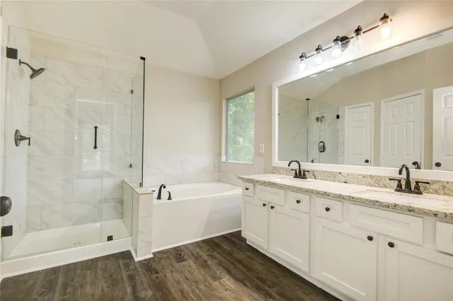 a spacious bathroom with a granite countertop tub sink shower and mirror