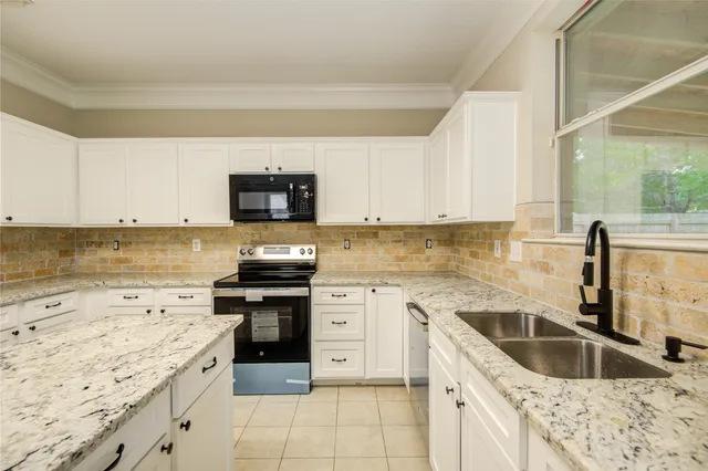 a kitchen with granite countertop a sink stove and cabinets