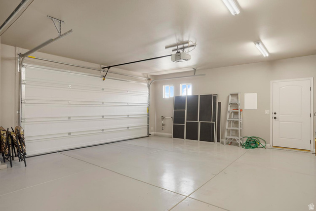 1587 Whitestone Drive St. George, UT 84790 - Photo 25 of 36 Two-car garage featuring a sectional garage door, epoxy-coated concrete flooring, two transom windows, recessed lighting, and a side access door