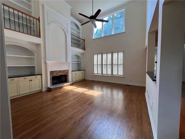 wooden floor in an empty room with a fireplace and a window