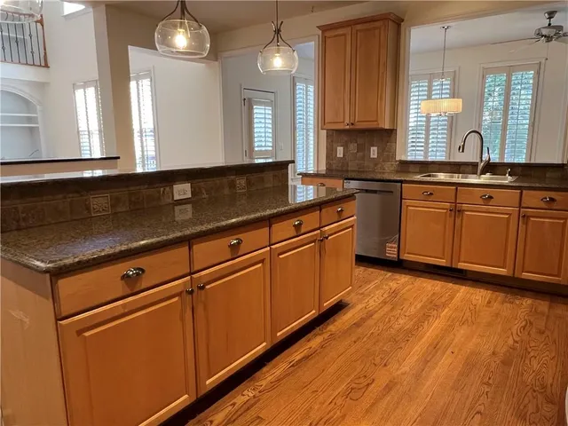 a large kitchen with stainless steel appliances granite countertop wooden cabinets a sink a stove a dining table and chairs