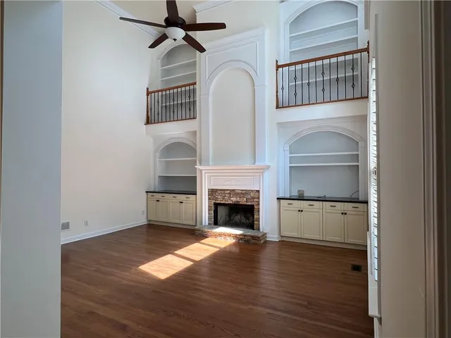 a kitchen with stainless steel appliances kitchen island granite countertop a stove top oven a sink a refrigerator white cabinets and wooden floor