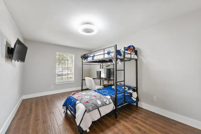 a bed room with a bed window and a flat tv screen on a dresser