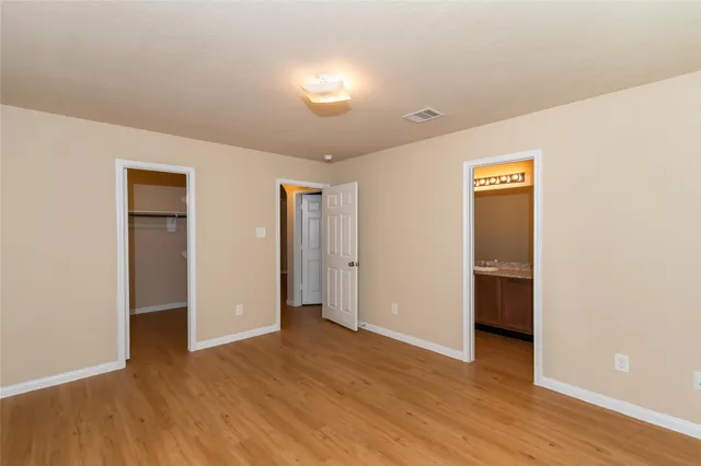 a view of an empty room with wooden floor and closet
