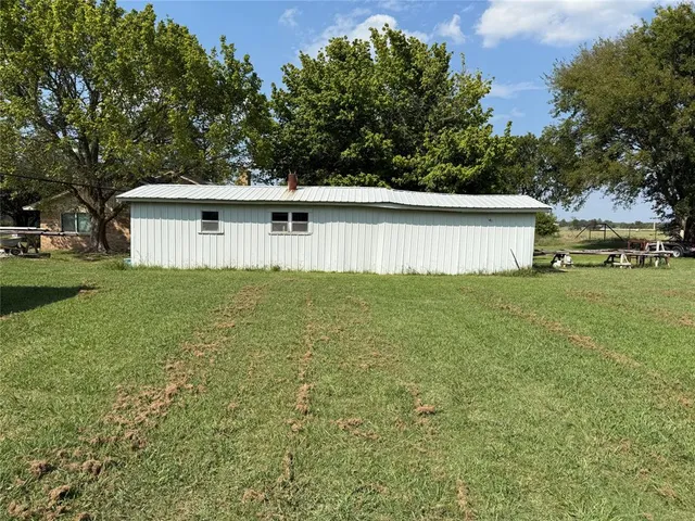 a backyard of a house with plants and large trees