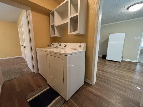 a utility room with wooden floor washer and dryer