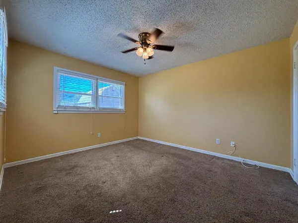 an empty room with windows and ceiling fan