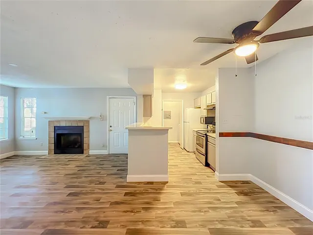 a view of kitchen and empty room with wooden floor