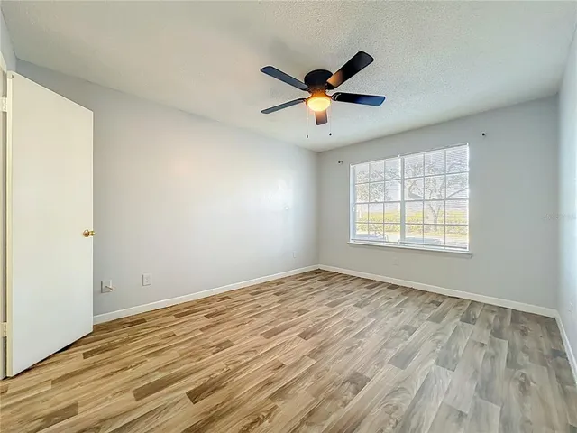 a view of empty room with wooden floor and fan