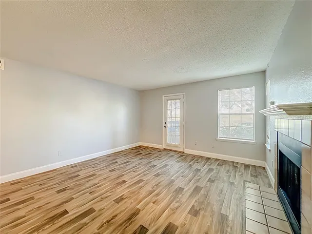 wooden floor fireplace and windows in an empty room