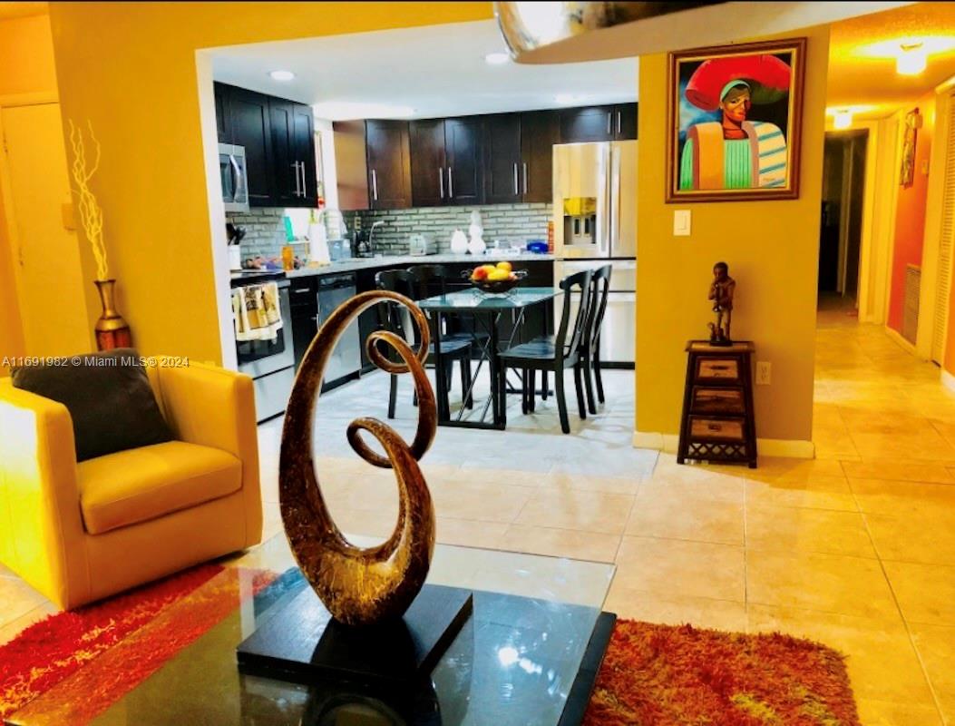 740 Northeast 199th Street, Unit 206G Miami, FL 33179 - Photo 3 of 14 a living room with furniture a table and kitchen view