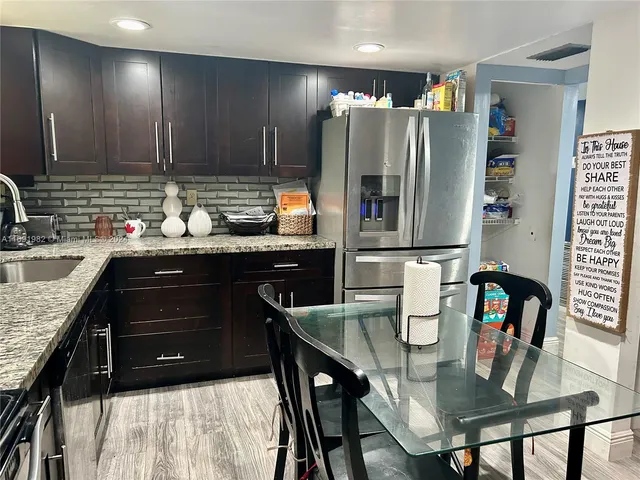 a kitchen with stainless steel appliances granite countertop a sink refrigerator and microwave