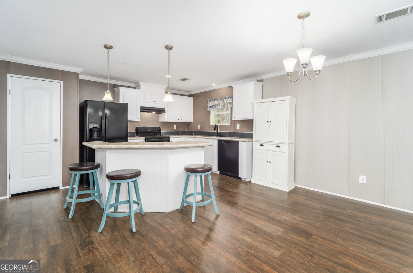6911 Old Hortense Road Hortense, GA 31543 - Photo 5 of 19 a kitchen with kitchen island granite countertop a table chairs refrigerator and microwave