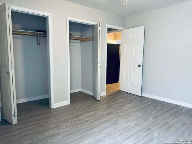 an empty room with wooden floor & closet area