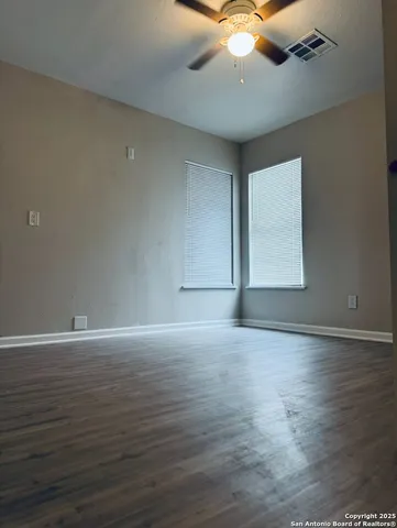 a view of an empty room with window and wooden floor