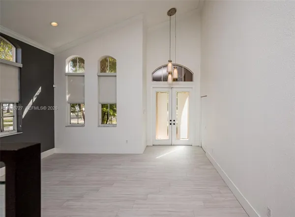 a view of an empty room with window and wooden floor