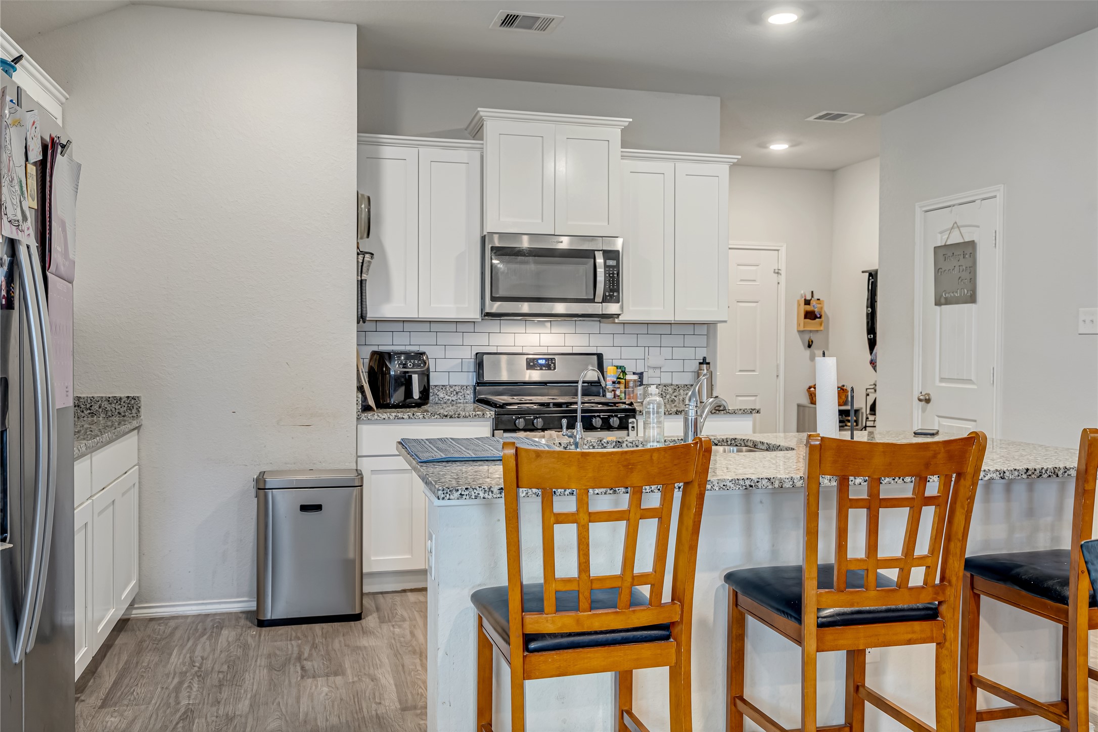 8022 Front Nine Lane Navasota, TX 77868 - Photo 11 of 30 a kitchen with stainless steel appliances granite countertop a refrigerator a stove top oven a sink dishwasher and white cabinets with wooden floor