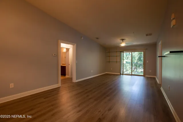 a view of an empty room with wooden floor and a window