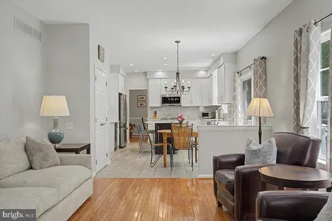 a living room with furniture and a dining table with kitchen appliances