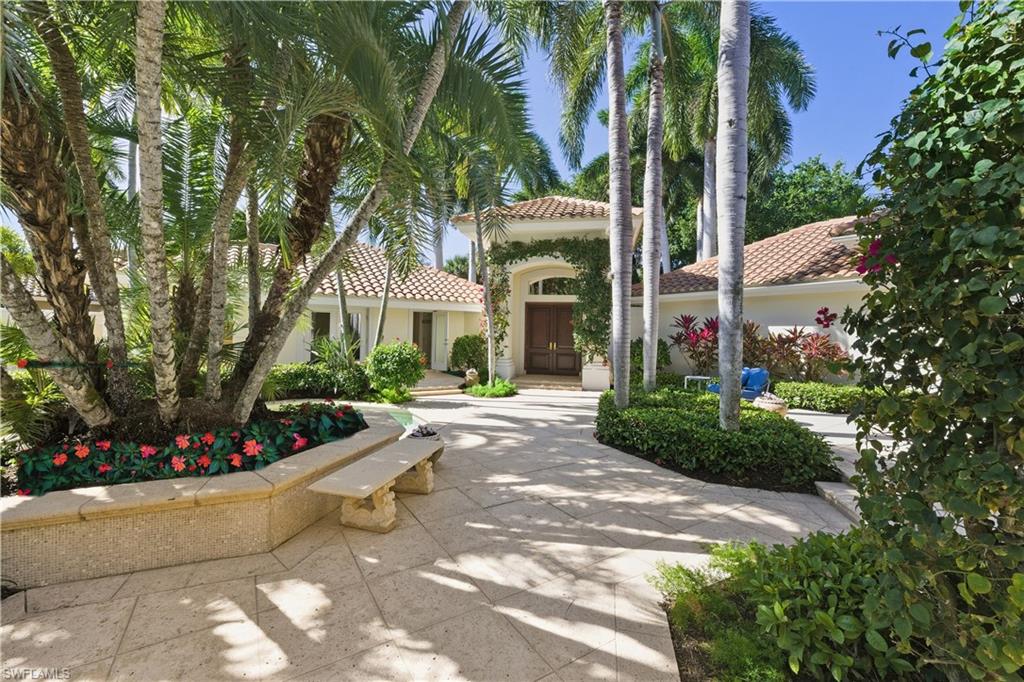 9264 Sweetgrass Way Naples, FL 34108 - Photo 8 of 40 a view of a white house with a yard and potted plants