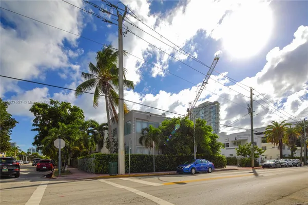 a view of a brick house with a small yard and large trees