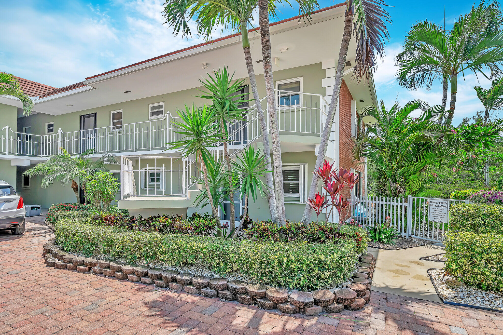 711 Northeast Harbour Terrace, Unit 4120 Boca Raton, FL 33431 - Photo 7 of 37 a front view of yellow house with a small yard and potted plants