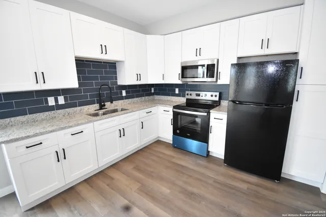 a kitchen with a sink white cabinets and stainless steel appliances