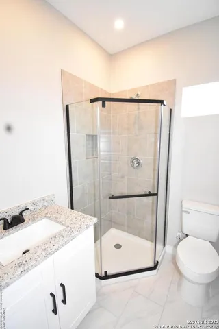 a bathroom with a granite countertop shower a toilet and a sink