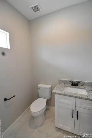a bathroom with a granite countertop toilet and a sink
