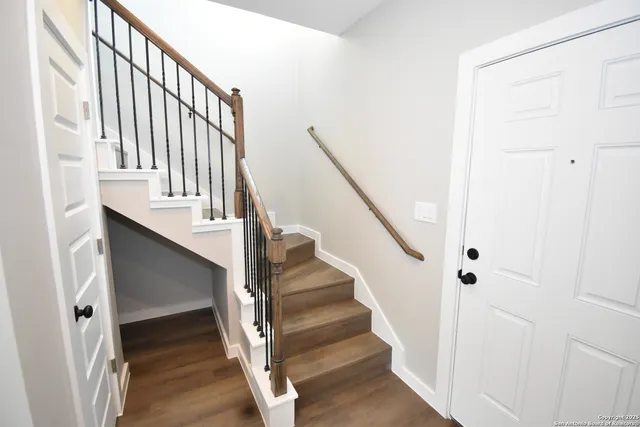 a view of staircase with wooden floor and white walls